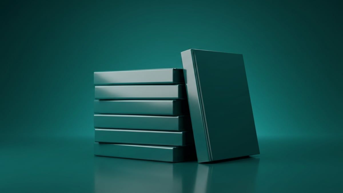 Laptop showing a keyword research table beside a stack of paperback books